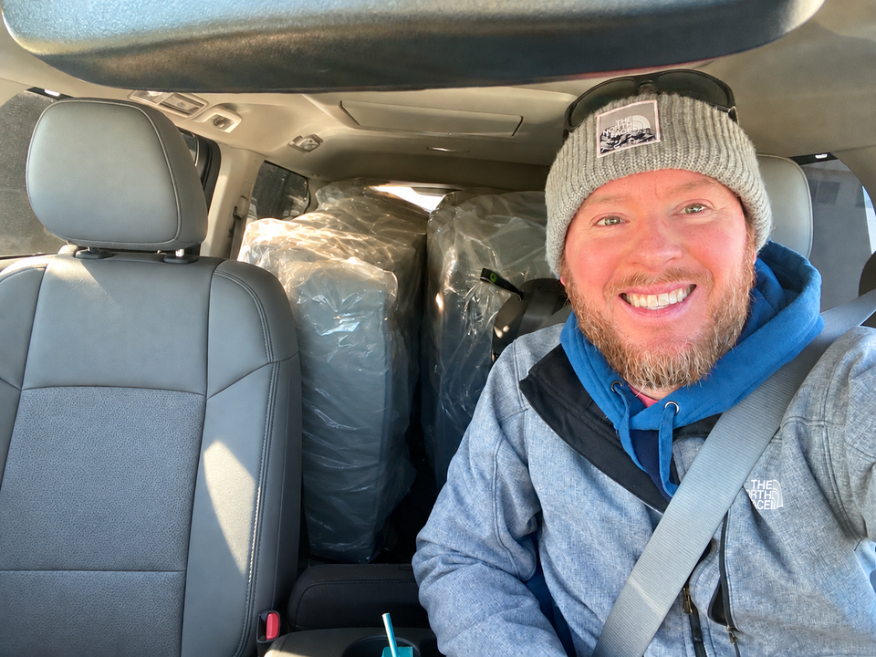 Stephen Meyer in his truck with wrapped mattresses behind the front seats.