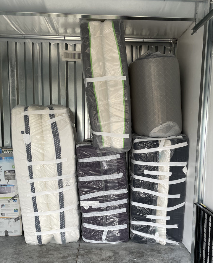 Returned mattresses wrapped in plastic and grouped in a storage unit.